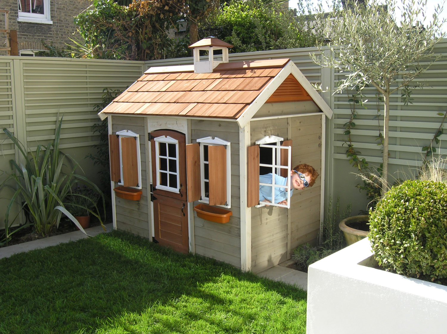  Child having fun in play house in a newly landscaped garden in London. 