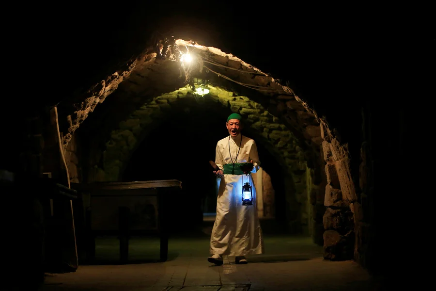 A Musaharati , or dawn awakener, strikes his drum to wake observant Muslims for their overnight sahur , or last meal, before the day's fast during Ramadan in Sidon's Old City in south Lebanon just before dawn, June 8, 2016. From The Atlantic, 'Images of Ramadan 2016. https://www.theatlantic.com/photo/2016/06/images-of-ramadan-2016/486212/