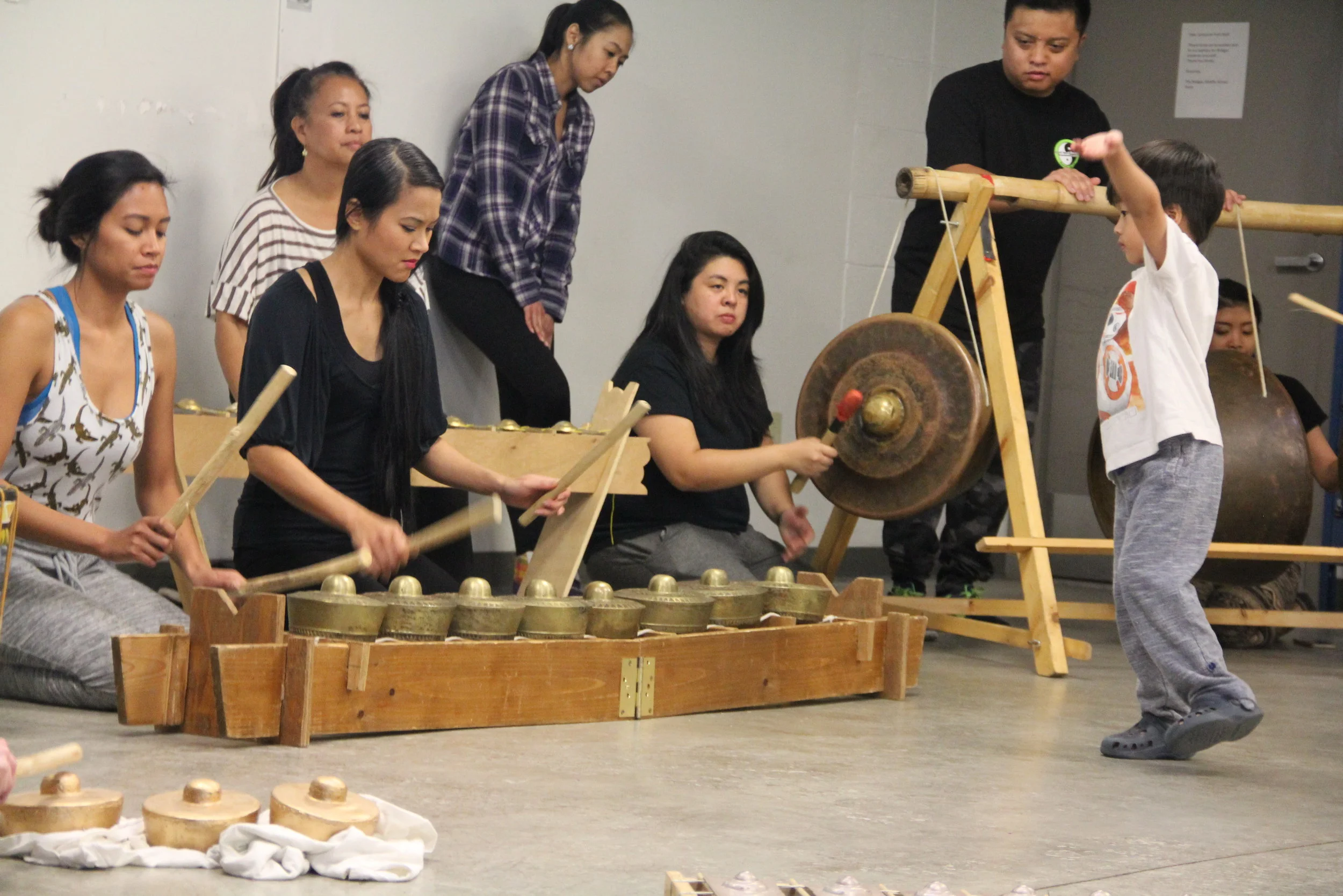 Participants have a hand at playing the kulintang and the gong, while a young participant practices pangalay .
