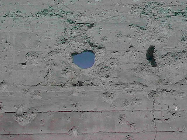 Mysterious hole blasted in concrete wall