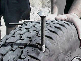 The puncturing bolt is almost completely removed from the tire.