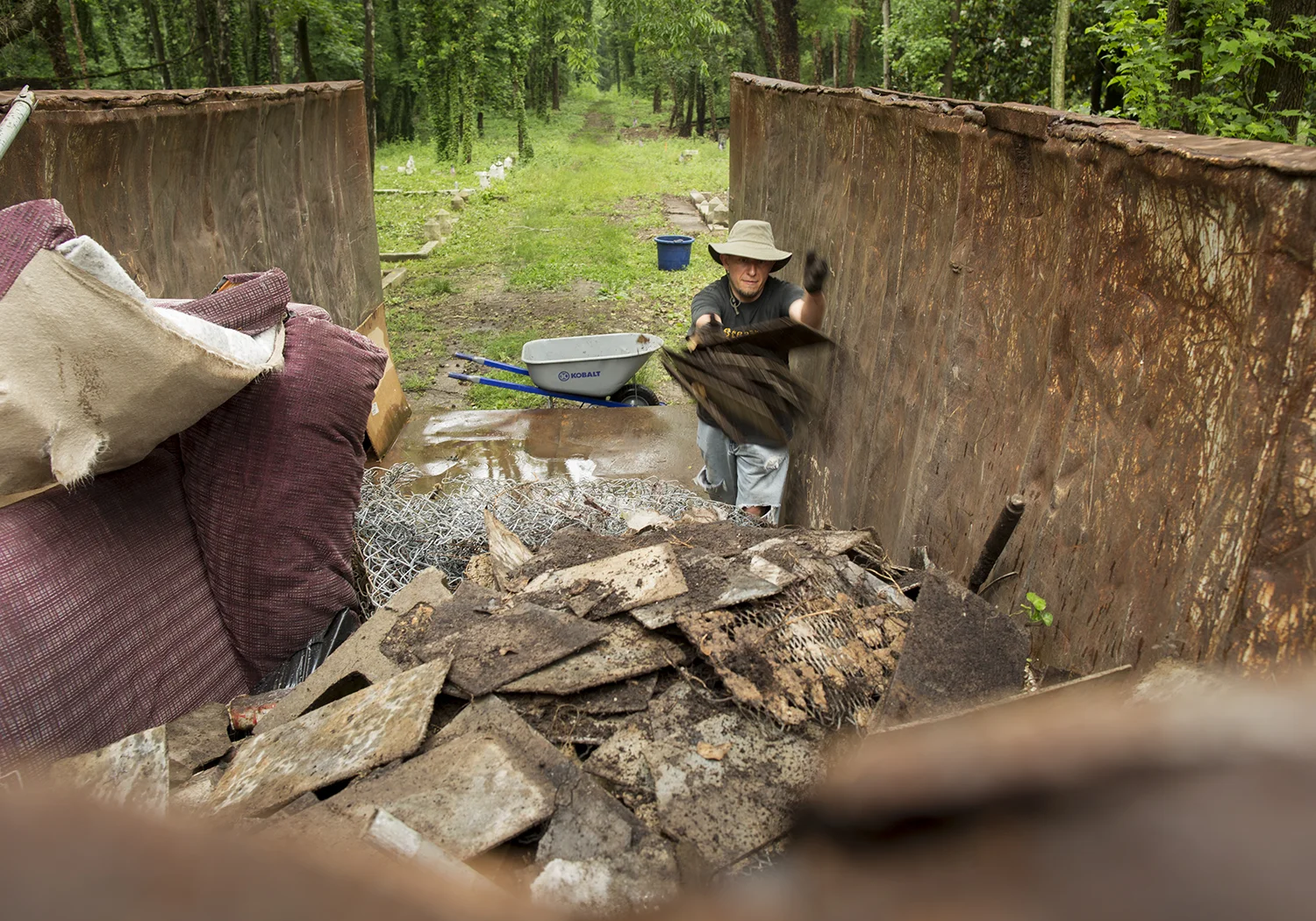 After helping to excavate much of the illegally dumped trash from one section of the cemetery, volunteer Justin Curtis (who moved back to Ohio in August 2015 but makes regular trips to Richmond to work at East End) tosses it into the dumpster. Henrico County has since hauled the junk away. East End Cemetery, Henrico County, Virginia, May 2016. Photo: BP