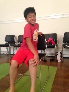 How to : While sitting in your seat, uncross your knees and ankles and place your left hand on your opposite knee. Place your right hand on the seat back or seat behind you. Inhale, and sit tall . Exhale, and twist towards your right, keeping the shoulders open and not slumped. Repeat on the other side. Do about 2-4 times. Kids can blow out their breath as if blowing out a birthday candle and hold the twist the number of their age. So a 6 year old, can count to 6 and hold the twist for 6 seconds! Benefits: Increases flexibility in the shoulders and neck. Stretches and Strengthens the spine and increases blood circulation. 