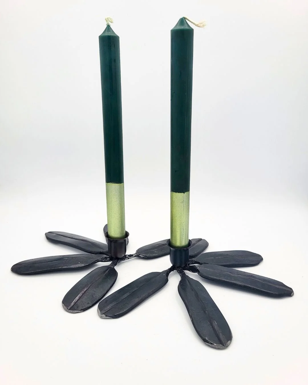 Two blue/grey rhododendron candlesticks with taper against a white background.