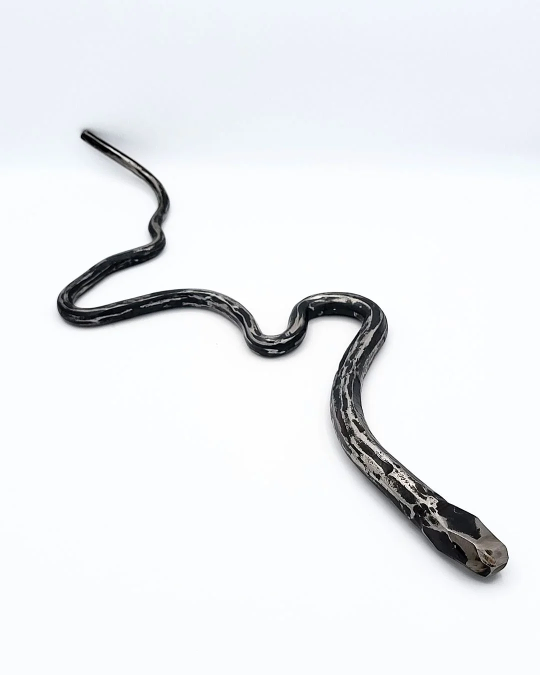 Hand-forged steel snake on a white background.