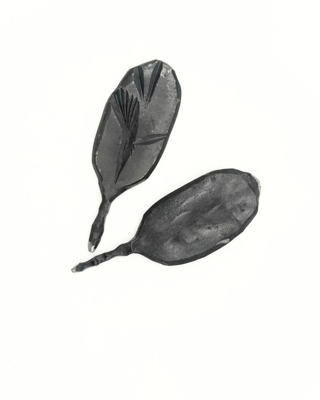 Two steel divot tools with leaf pattern for golf on a white background.