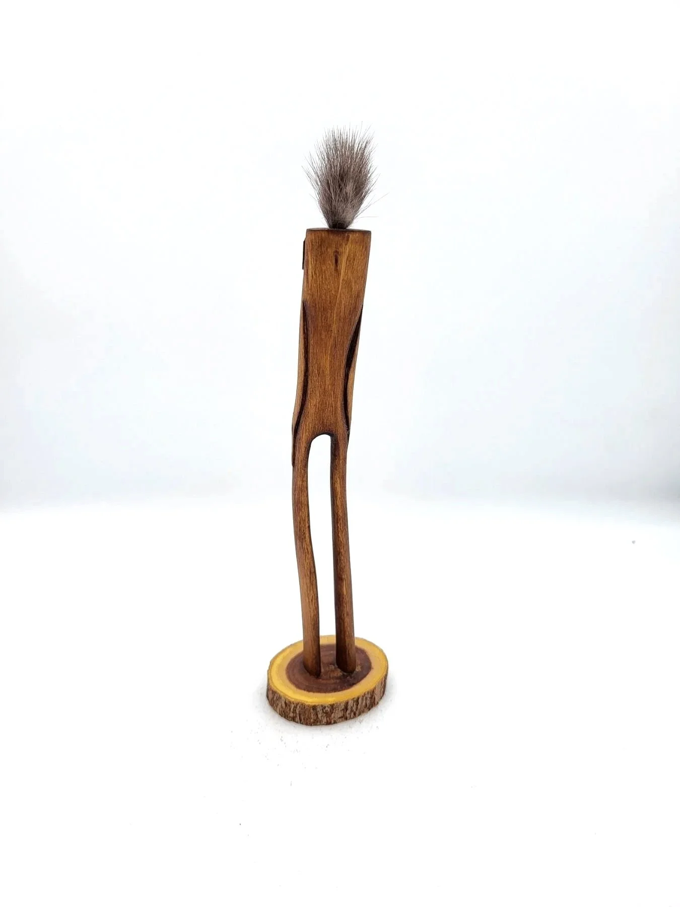 Hand-carved wooden tree creature with tufts of fluffy brown hair facing backwards.