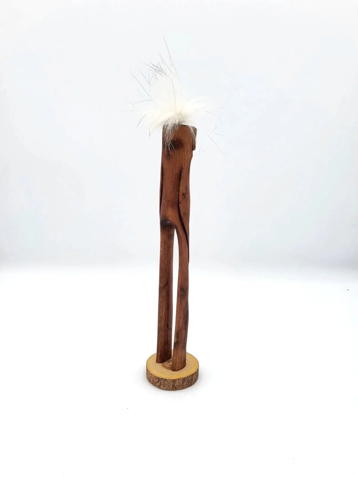 Hand-carved wooden tree creature with fluffy whisps of white hair facing backwards.