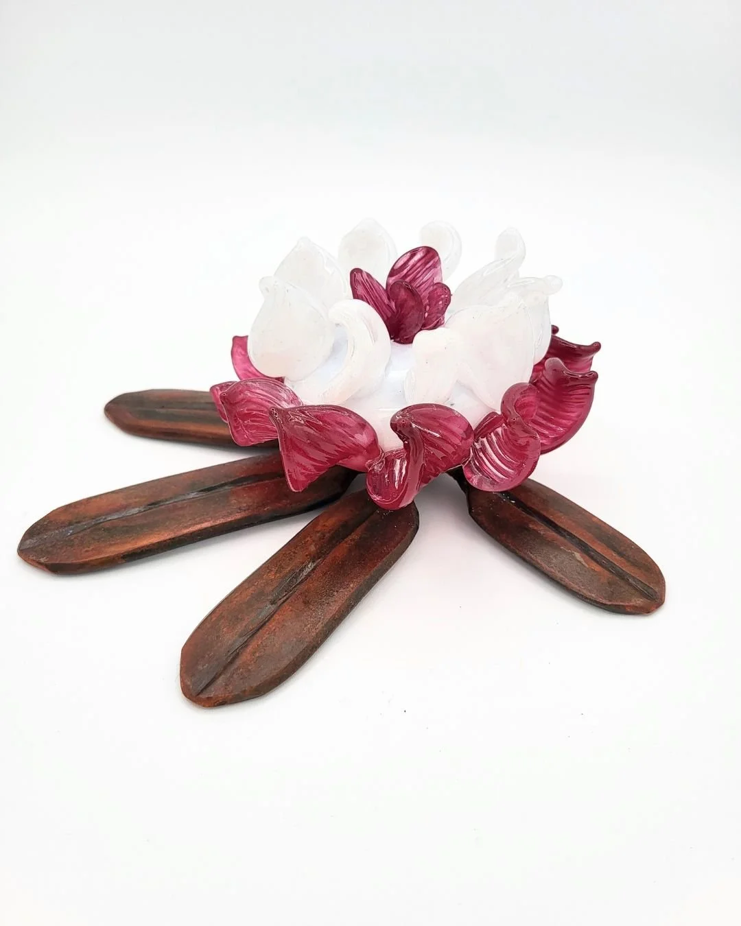 Hand-forged rhododendron leaf with pin and white glass flower nestled in the center against a white background.