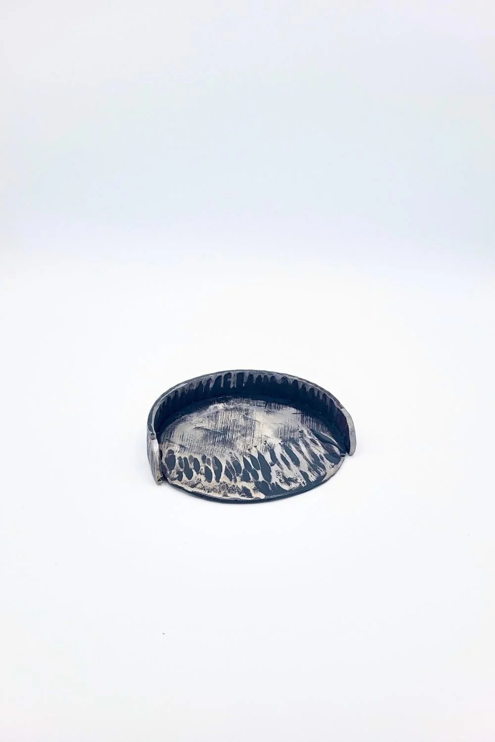 Hand-forged steel putting cup against a white background.