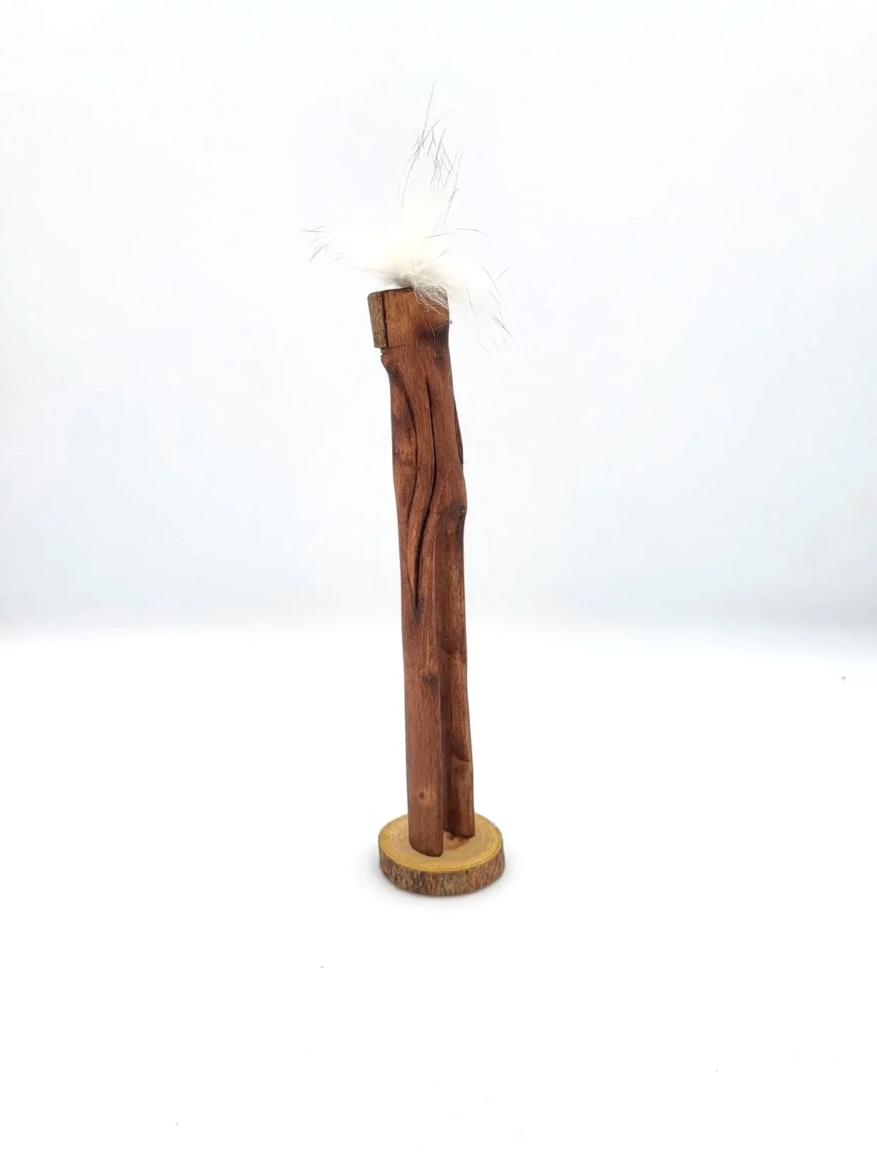 Hand-carved wooden tree creature with fluffy whisps of white hair facing sideways.