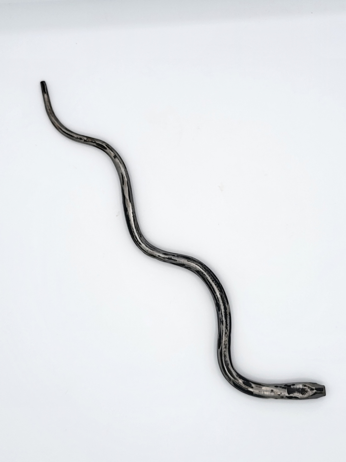 Steel hand forged snake against a white gradient background.