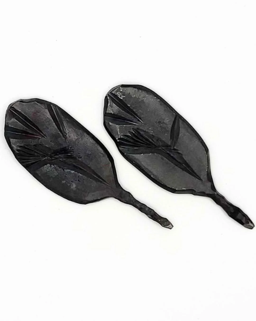 Two steel divot tools with leaf pattern for golf on a white background.