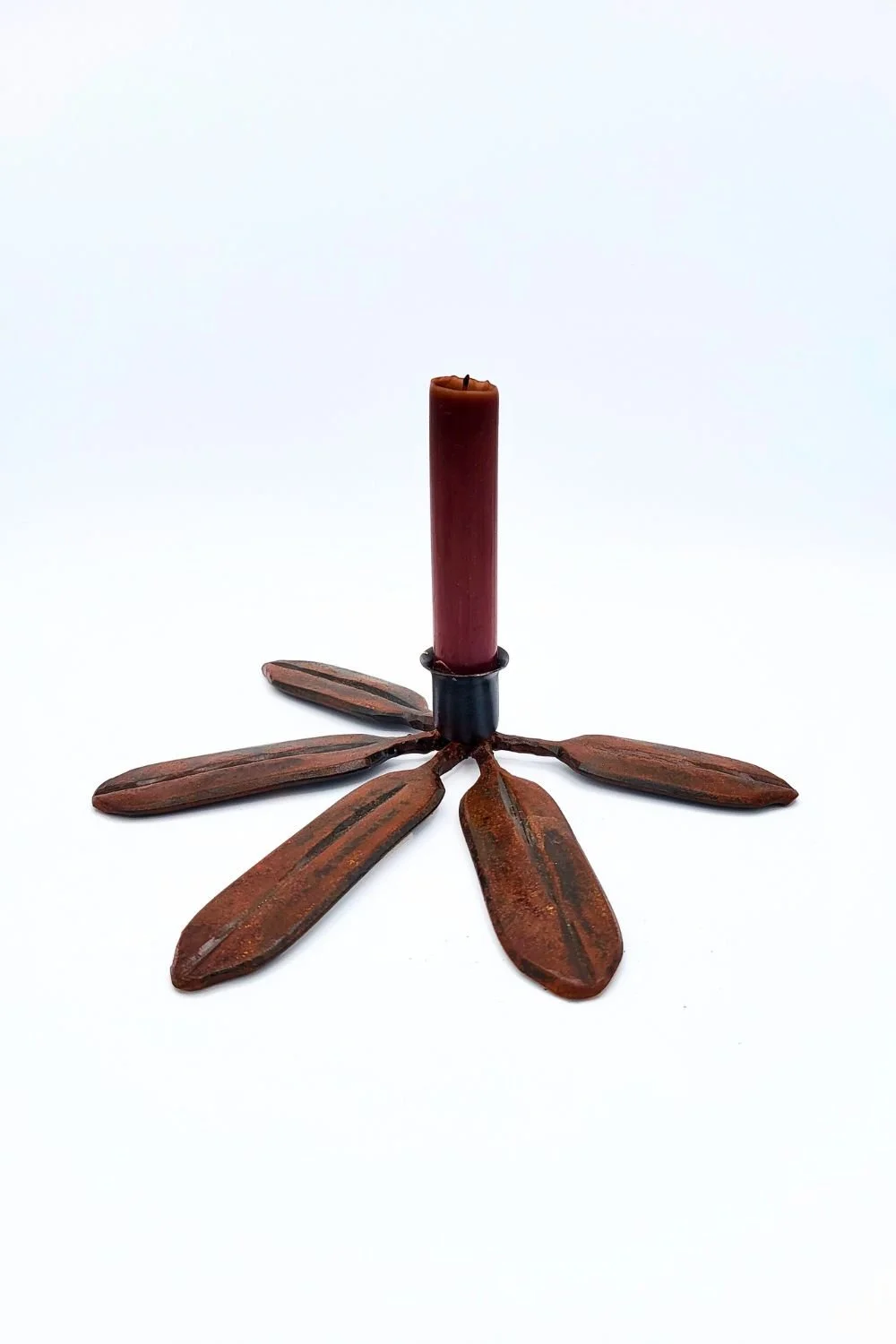 Single red/brown rhododendron candlestick with taper against a white background.
