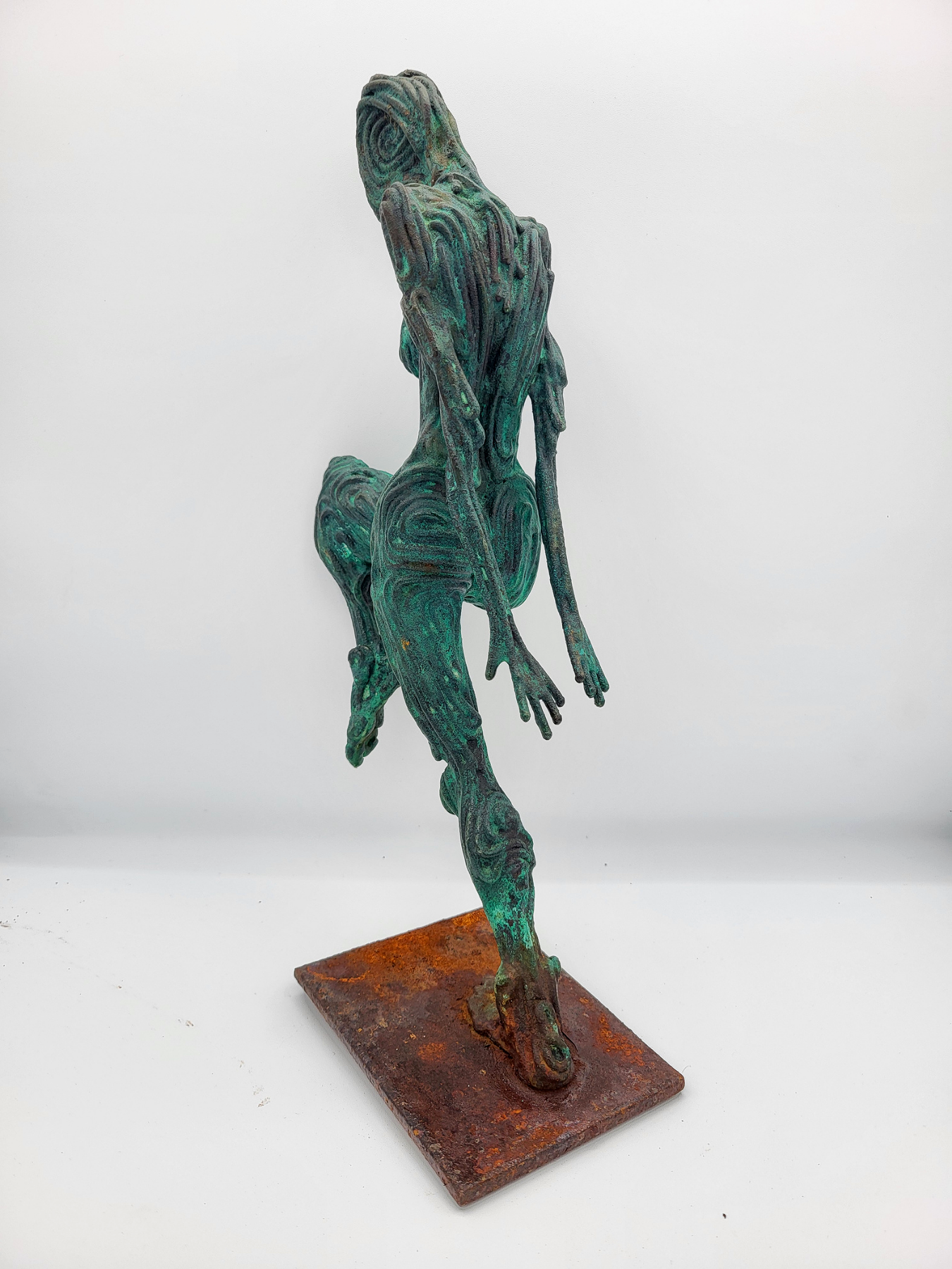 A sculpture of a solo dancer posed with hands forward and head down from front. Made by artist J. Aaron Alderman from steel round stock and finished with a copper patina.