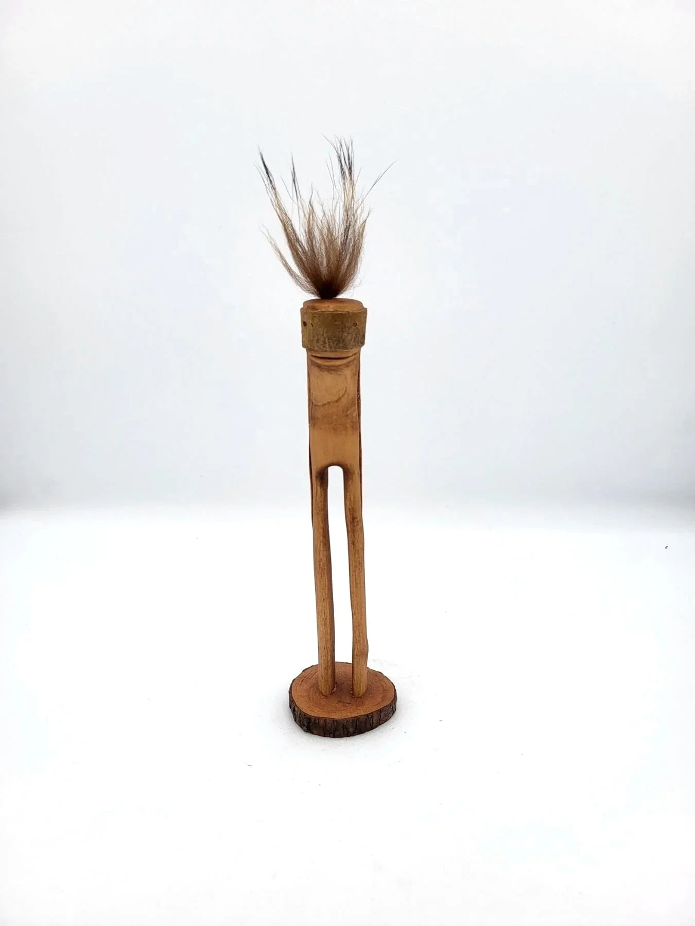 Hand-carved wooden tree creature with tufts of brown hair facing front.