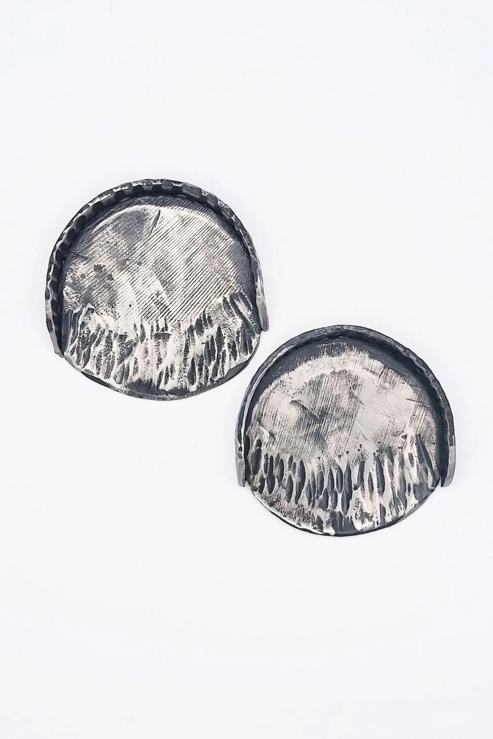 Two hand-forged steel putting cups against a white background.