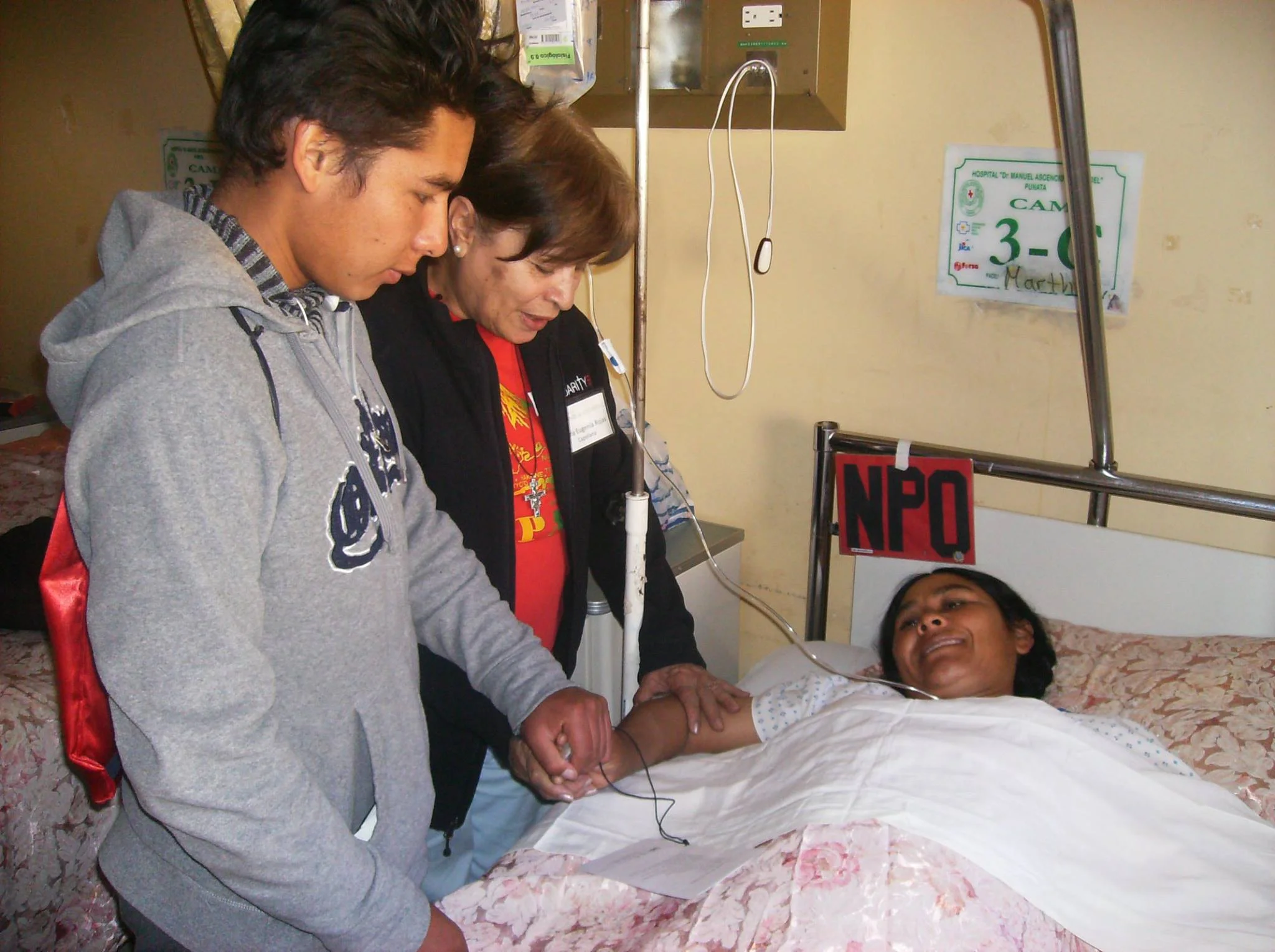 Puente de Solidaridad Board Member and Chaplain, María Eugenia Rojas, prays with a patient and her son.