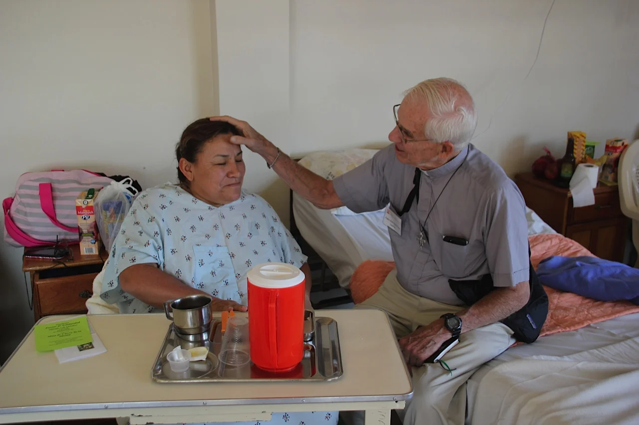 Fr. Bob visiting with a patient from the 2015 Multi-Specialty Mission Trip