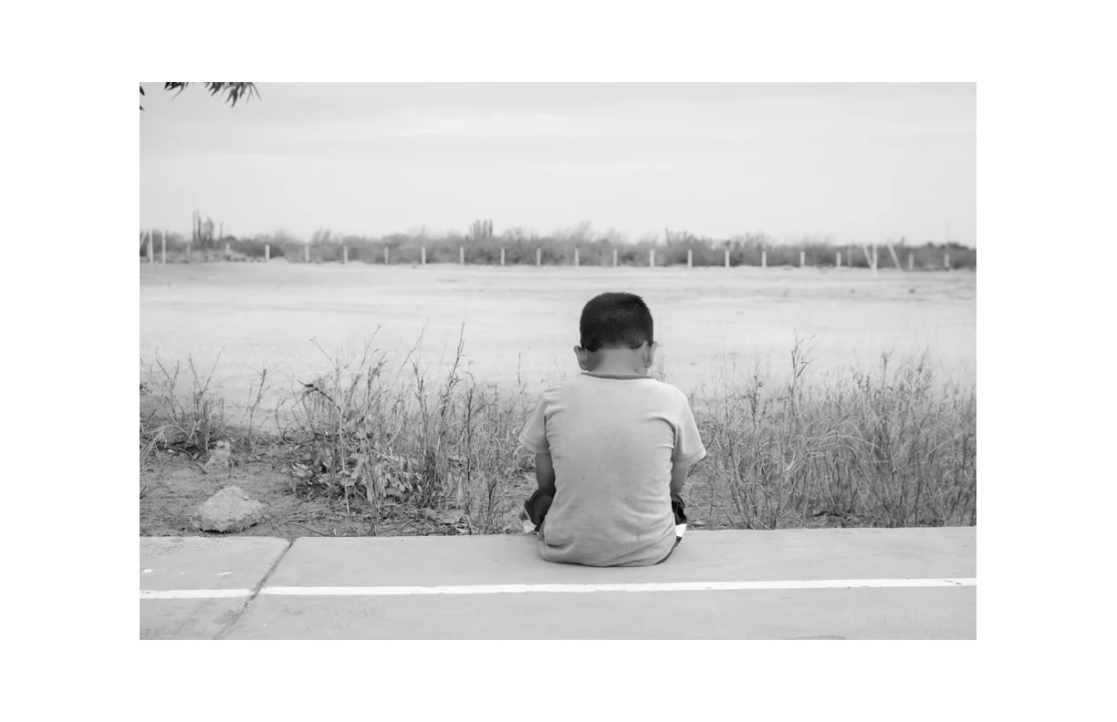 Armando alone (EMPALME, SONORA, MX) A quiet moment alone CAPTURED, ambiguous in it's emotion. the desert landscape reflecting a perceived isolation. Rancho del Nino orphanage is remote. It is situated at the end of a long road far from town. © Angelina Attwell