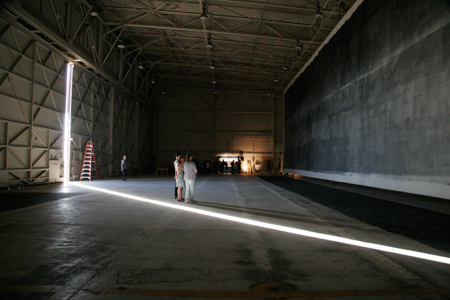 Admiring the Great Picture in the F-18 hanger with a strong beam of natural light framing the viewers.