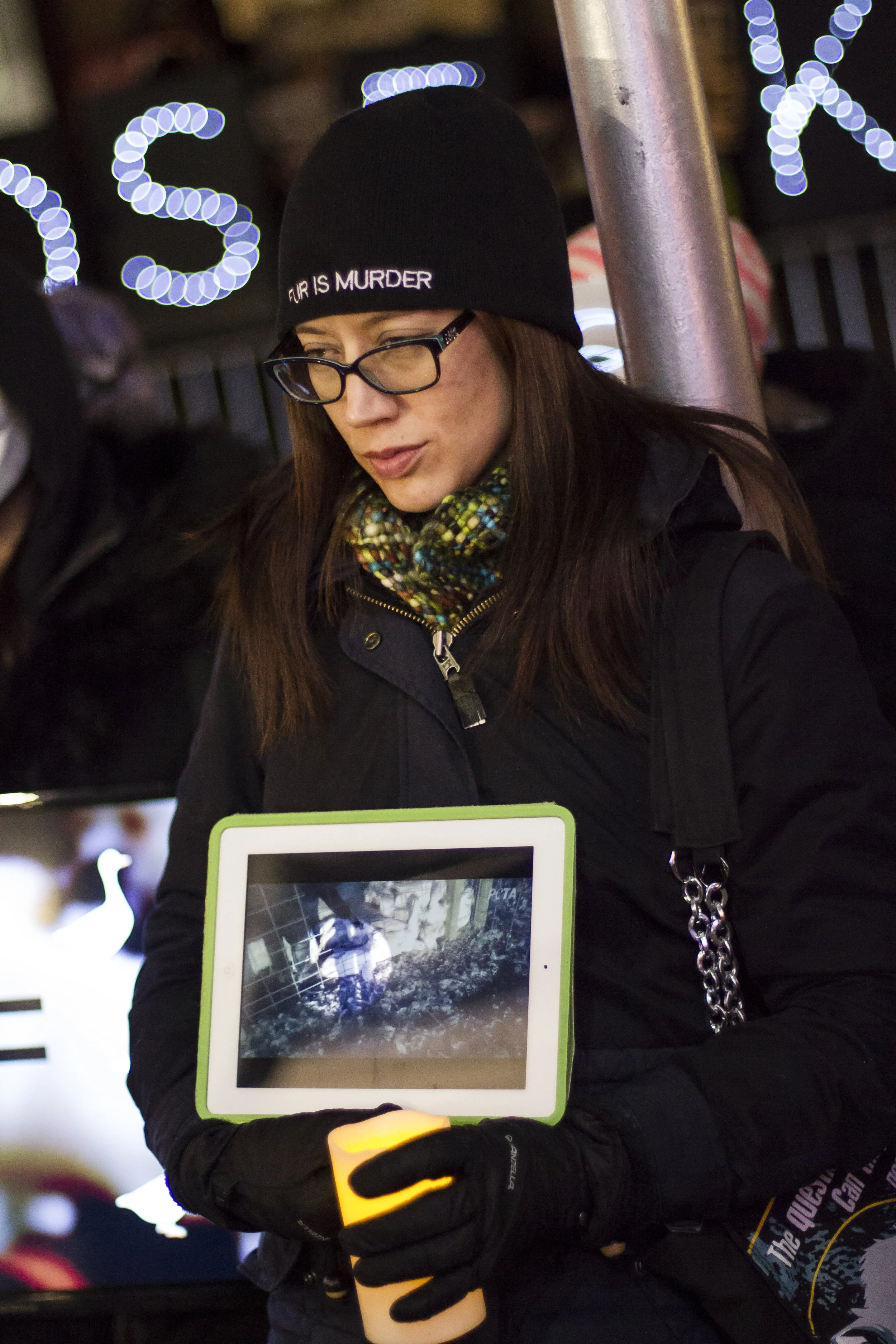 This activist holds an tablet that displays video footage of the barbaric methods used to obtain the body parts used in Canada Goose jackets. 