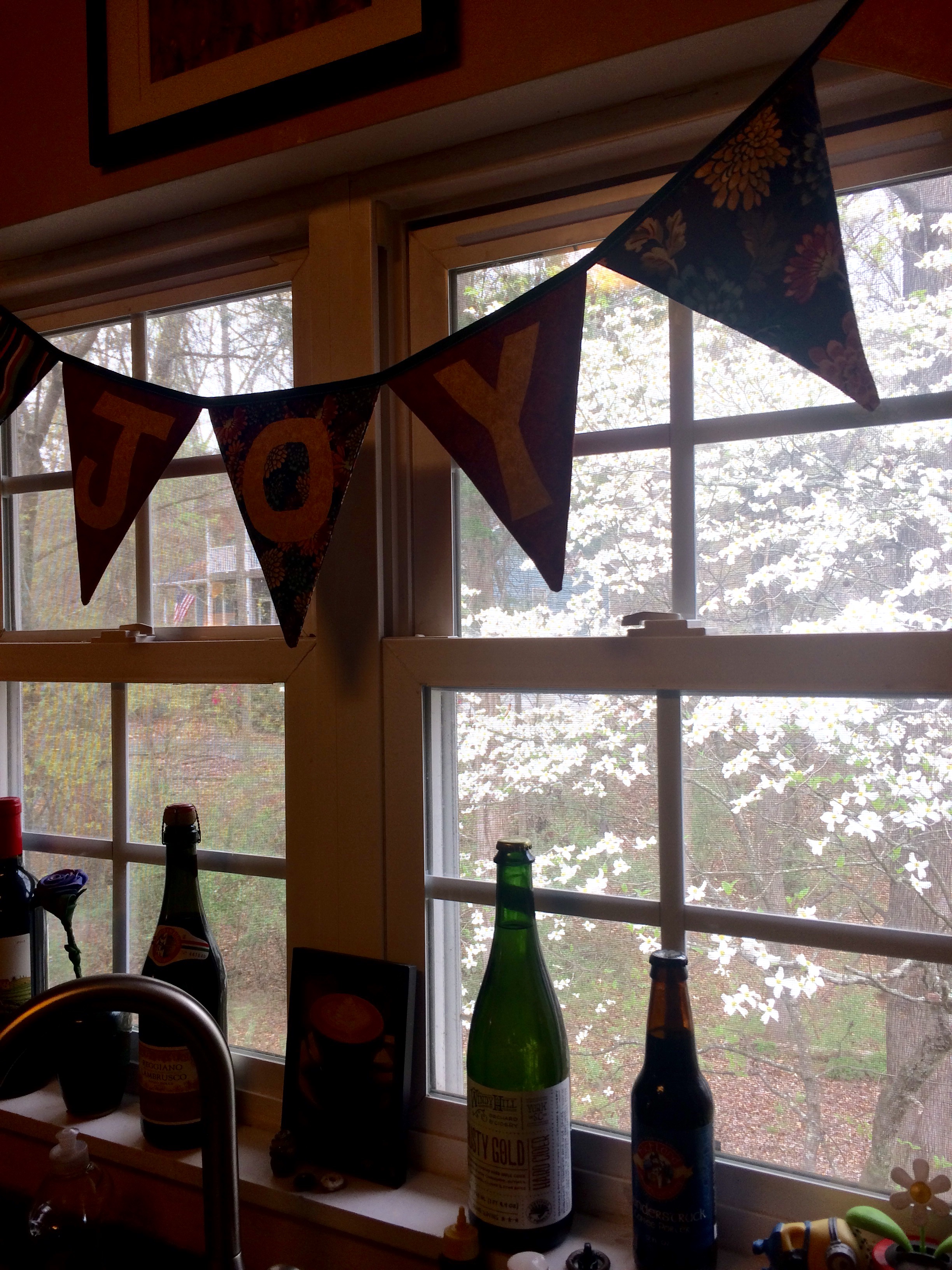 The view from my kitchen sink, with our lovely dogwood tree out back and my banner that says "Joy."