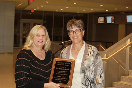 Yvette McCulley (L) accepts the award from Kelen Panec to honor posthumously Joseph Schwanebeck, Director of Education, Science Center of Iowa