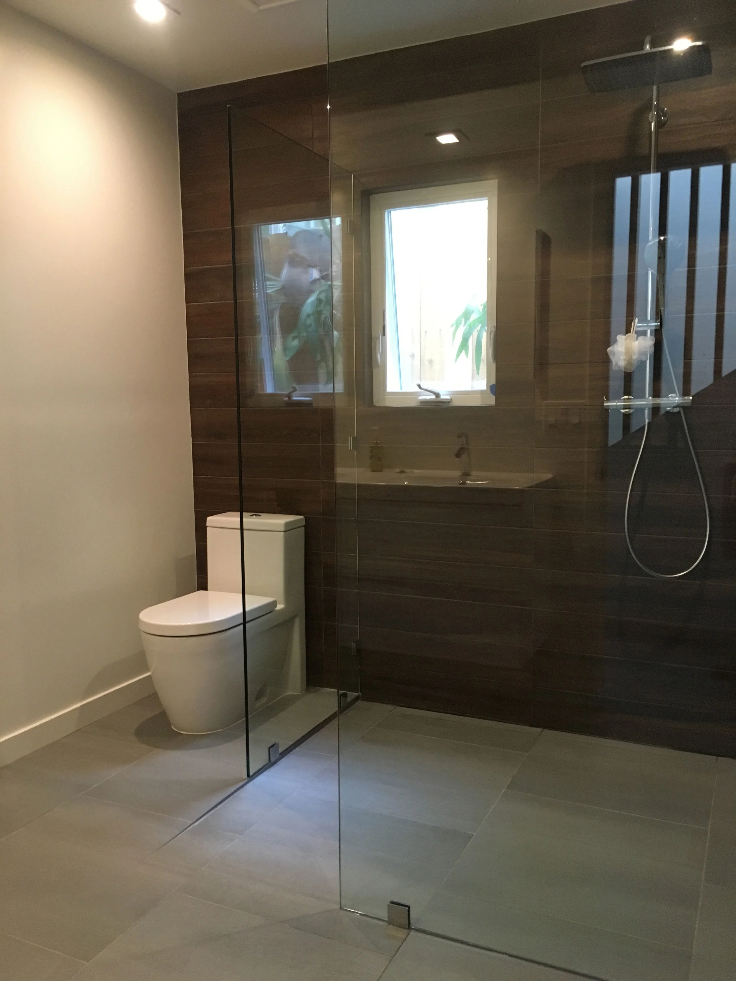 Bath with lateral drain, Duravit toilet, Hansgrohe shower. Ceiling ductwork was rerouted into a soffit above the sink and vanity allowing ceiling height to be raised to 10 ft.