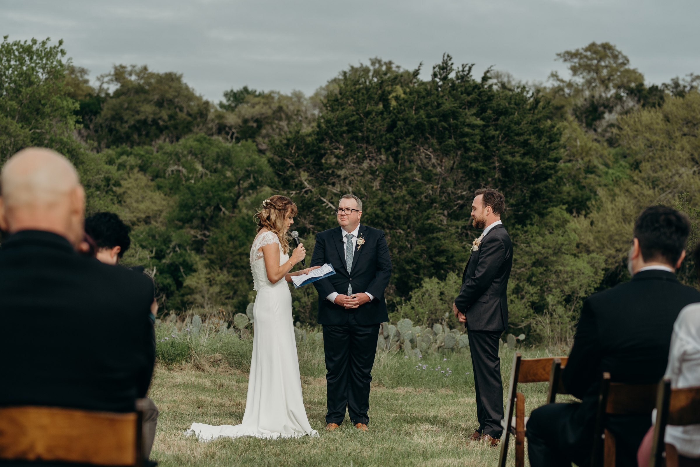  bride and groom exchanging vows wedding ceremony in field plant at kyle wedding venue austin texas 
