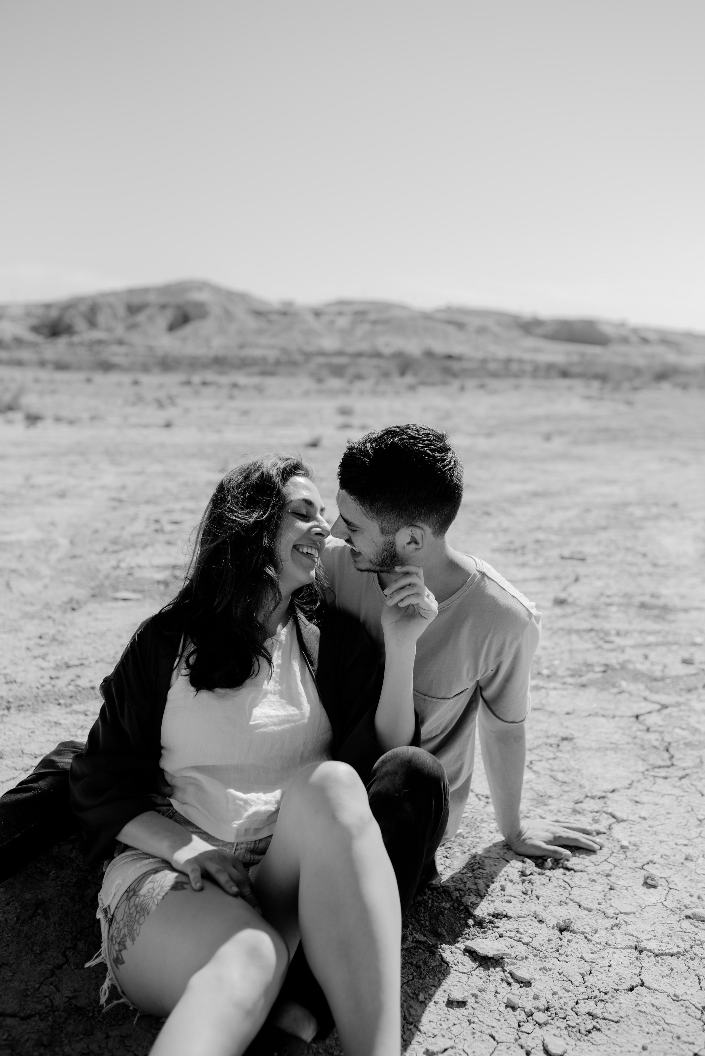  couple sitting on desert ground in terlingua west texas during big bend couples session 