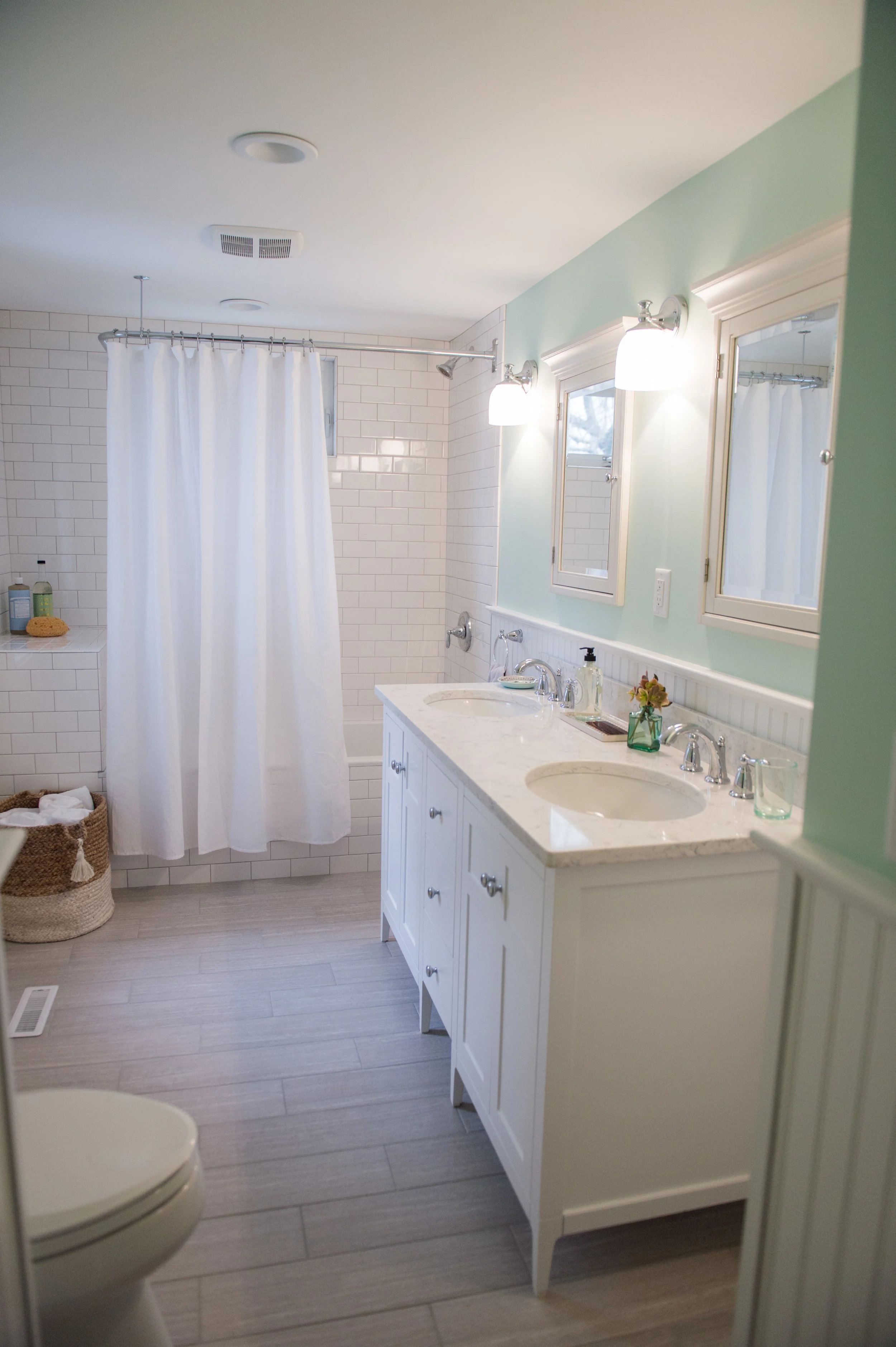 By knocking down the wall in between, our square footage doubled! This made room for a double vanity and a soaking tub/shower combo. A classic New England aesthetic with some modern touches was achieved through the finish and fixture selection. And that green...so pretty and calming!