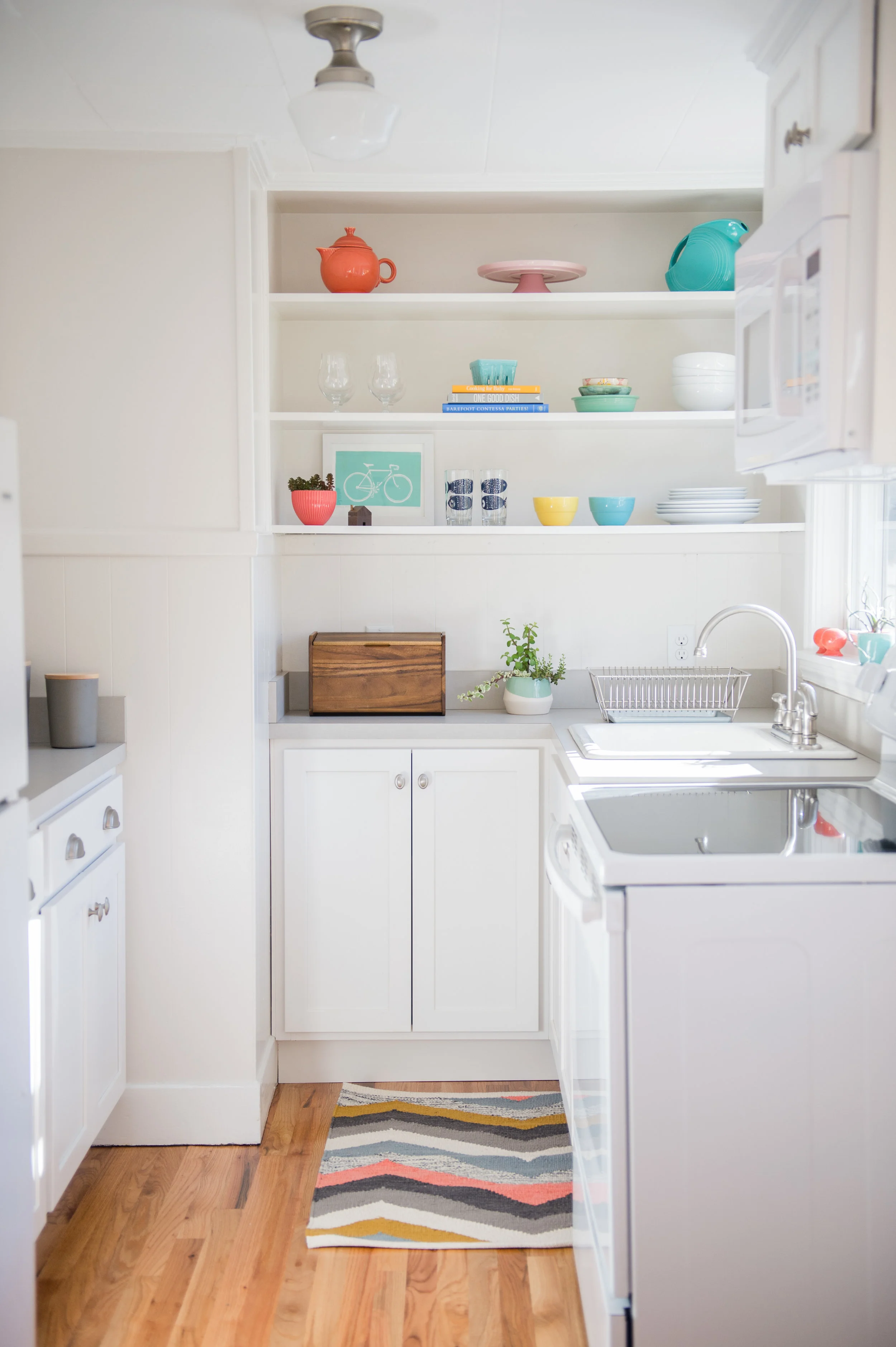 To keep costs down we specified a beautiful gray, linen-textured laminate for the counter tops and a clean white, shaker style cabinet door. New red oak floors were laid to match the rest of the home. Open shelving worked well for extra storage, particularly in this small space where upper cabinets would have felt too crowded.