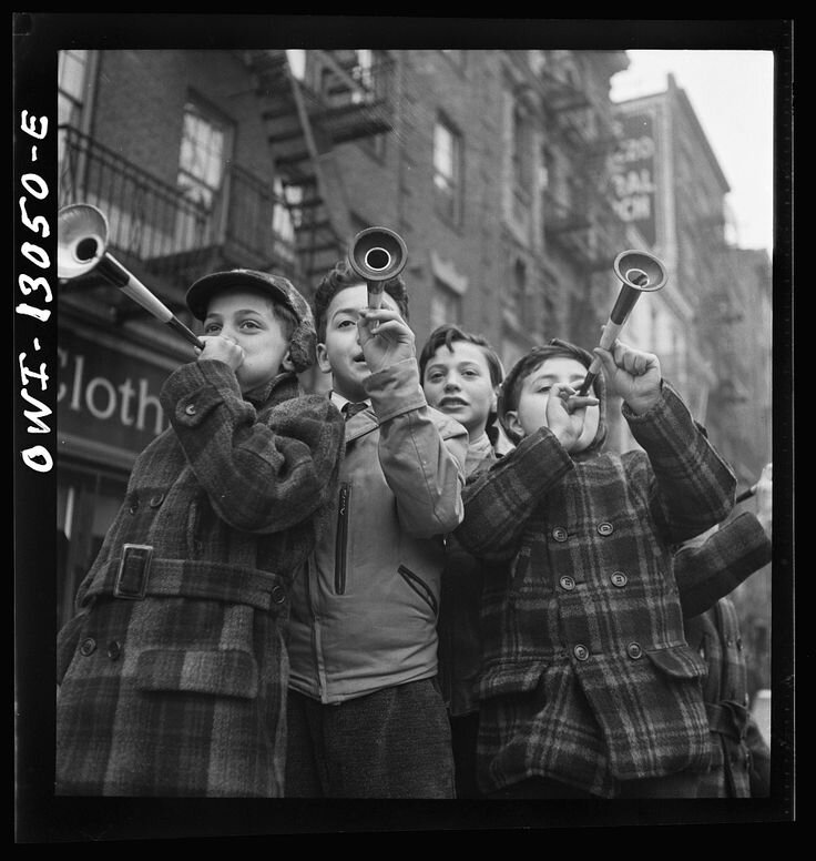 Blowing horns on Bleeker Street on New Year's Day; Photographer: Marjory Collins; Location: Bleeker Street, New York, NY, USA; Approximate Date: January 1943