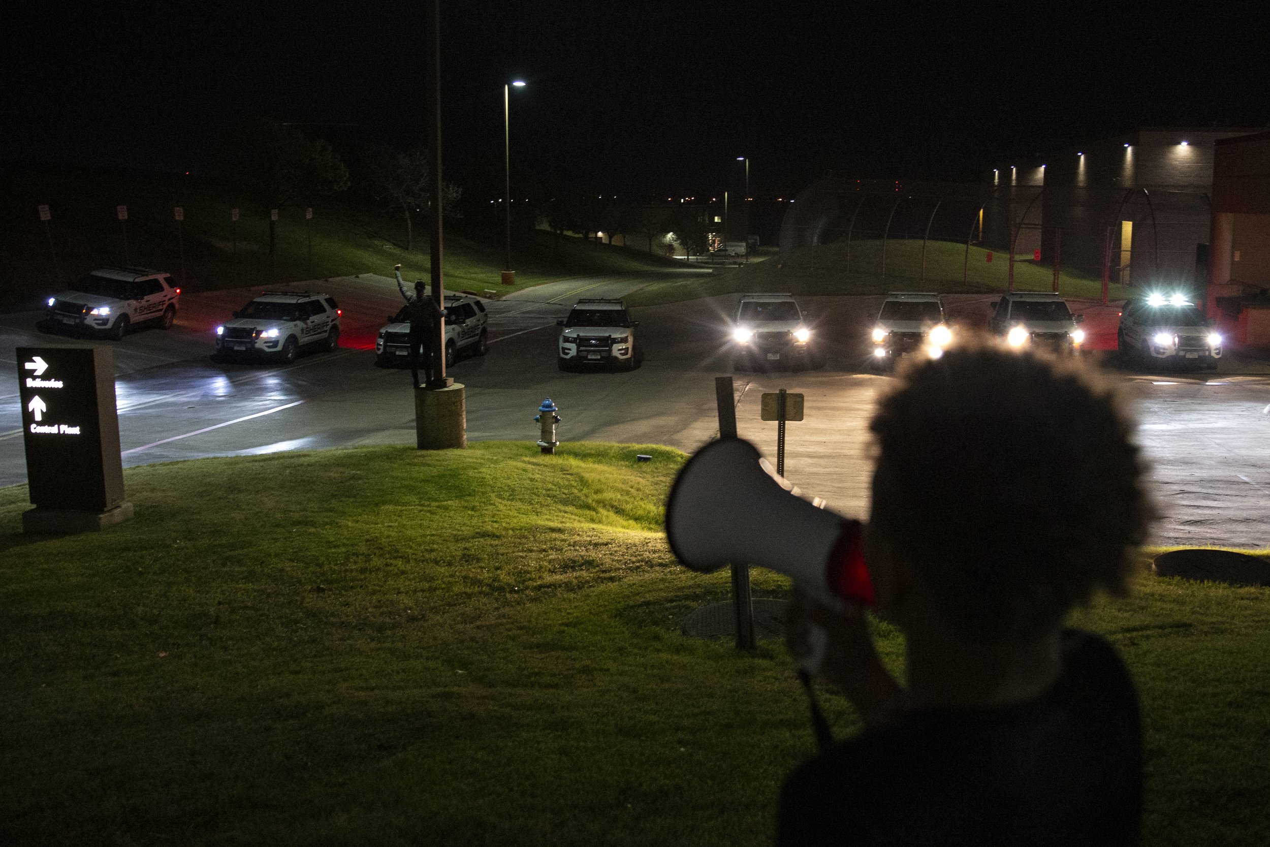  Renee White holds up a fist in front of the barricade of eight police cars as Elijah Lyons, Marvin Scott III’s 9-year-old nephew, leads a chant repeating Marvin’s name at the Collin County Jail.  The police moved them out of an area where they were 