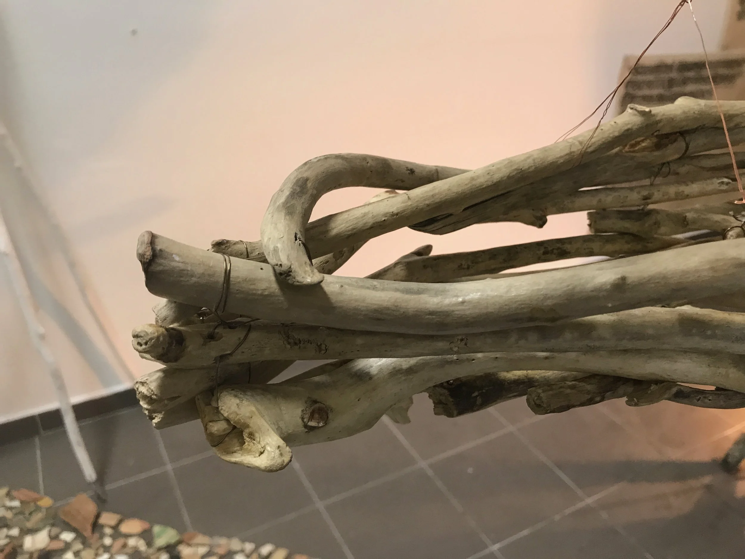 Copper wire is threaded through drilled holes to hold together bone-like driftwood with gilded wounds.