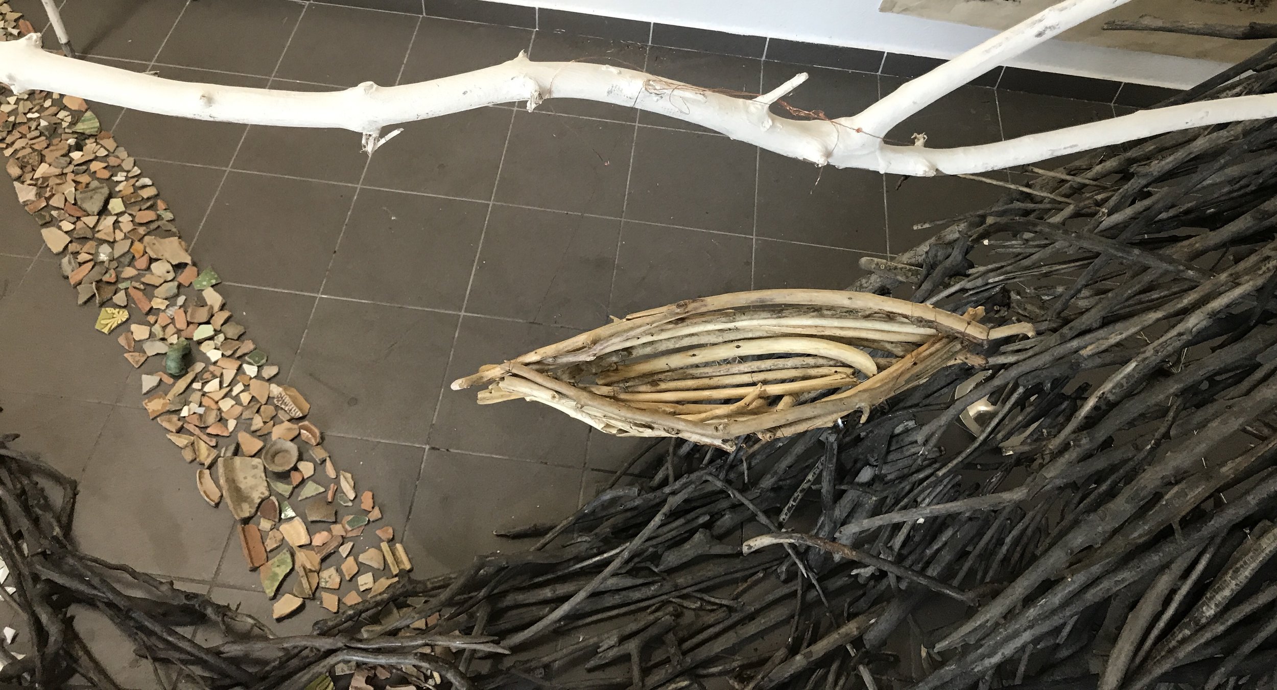 One of four boats made of driftwood and copper wire, each piece of wood burnished by hand. Three boats are suspended above the ‘river’ by thin wires from large natural wood tripods, which are painted white to more easily blend in the the gallery’s background. Installation is easily reconfigured to fit any space. If the background were a different color, the white stands should be painted to match it.