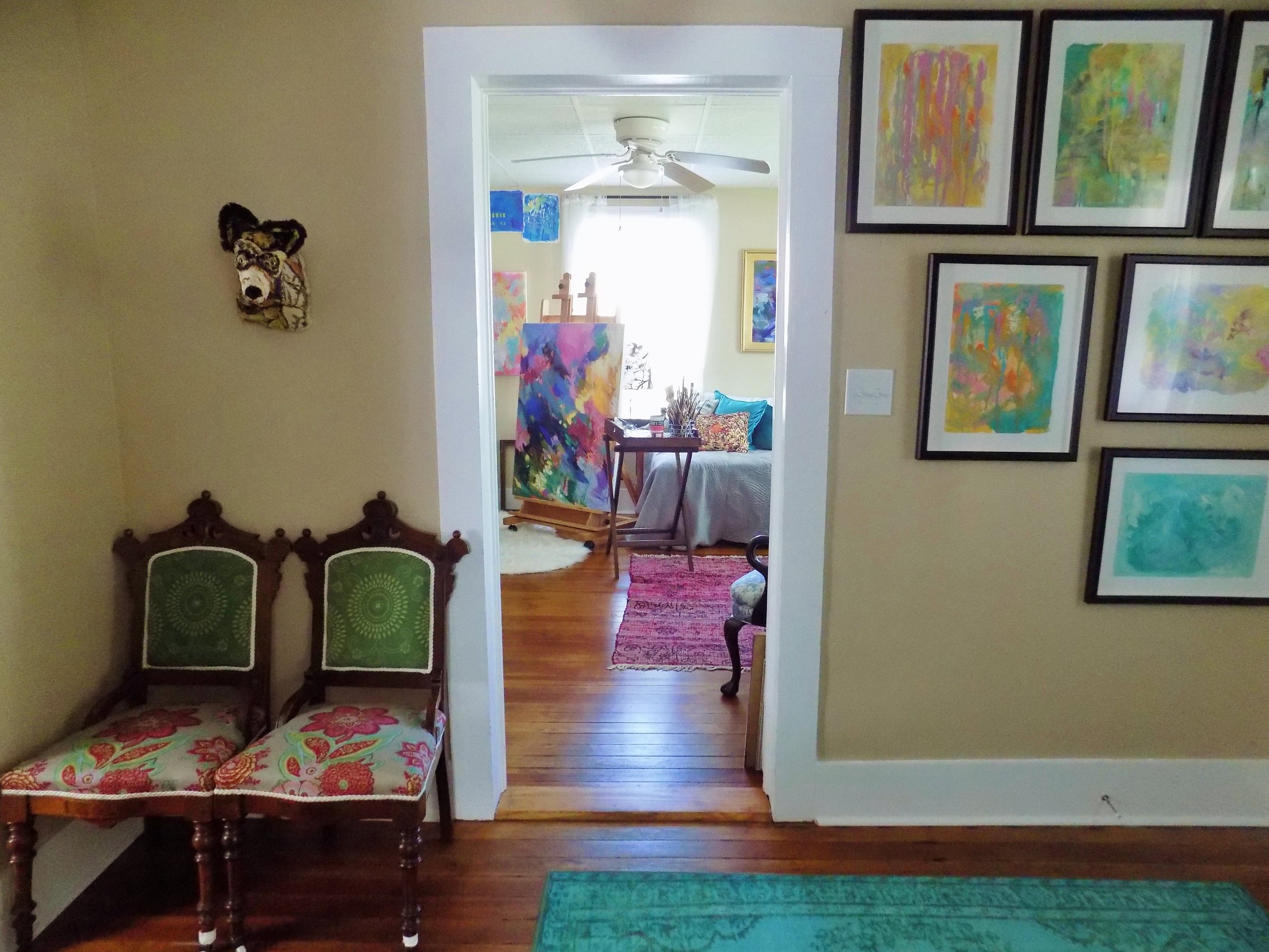  View from the front hall into the art studio.&nbsp; Two Victorian thrift store chairs (found for $40 and recovered by Lee's mother) anchor a fabric Coyote by Meredith Hadaway. A gallery wall of Lee's fluid art flanks the other side of the doorway. 