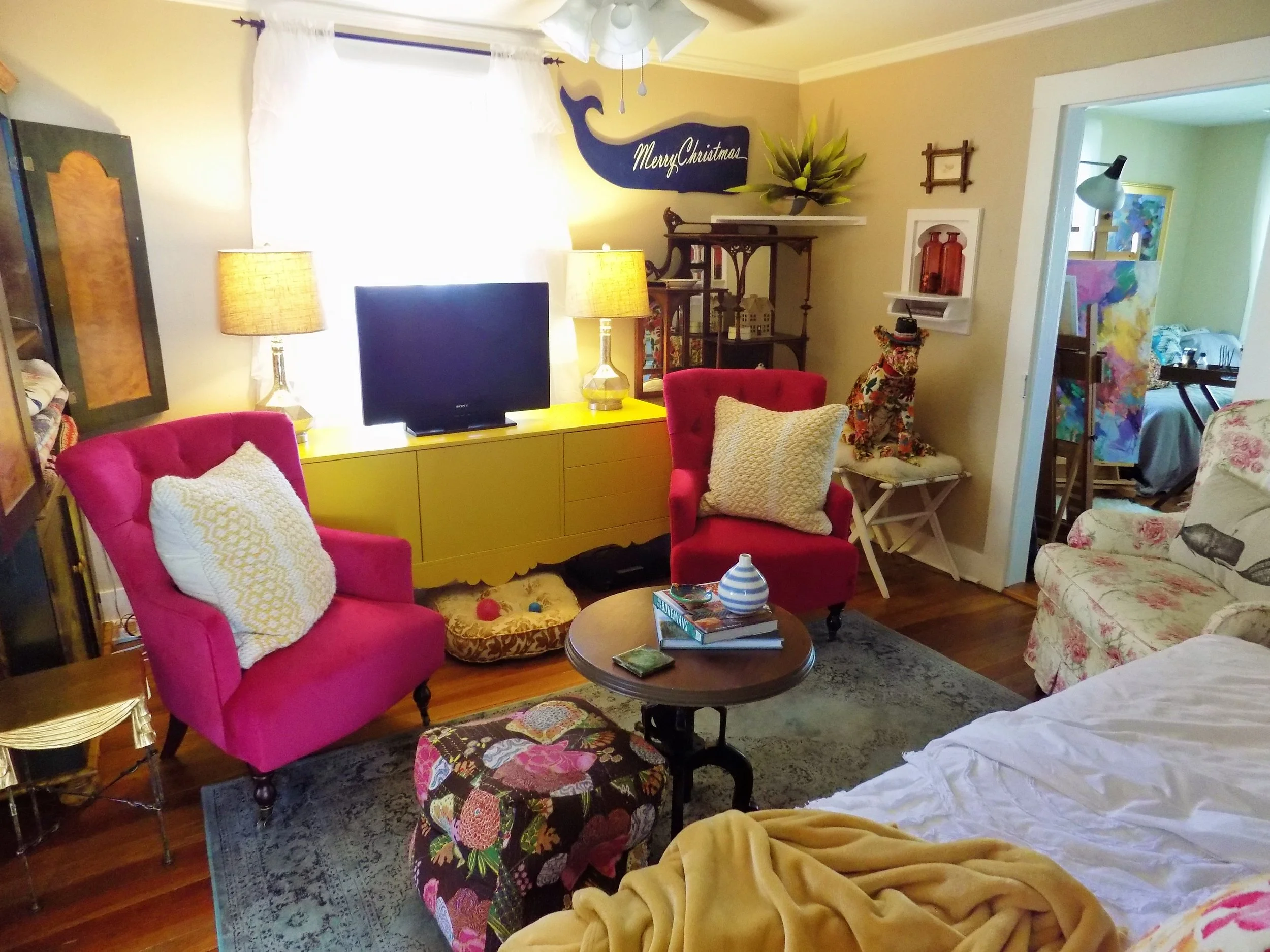  Two bright pink chairs flank a vivid yellow IKEA console surrounded by quirky antique finds 