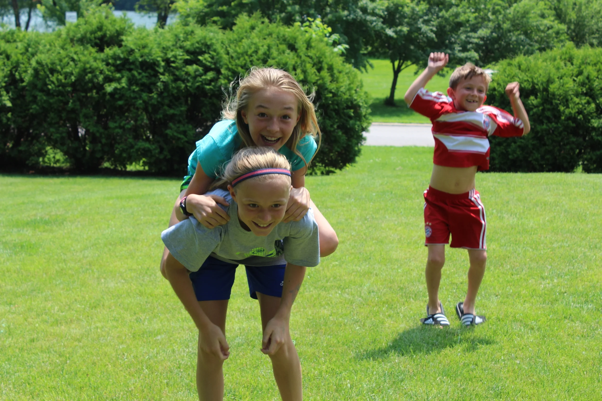 Lauren Ping gets a piggyback ride from her sister Lauren, while younger brother Jamison jumps in the background.