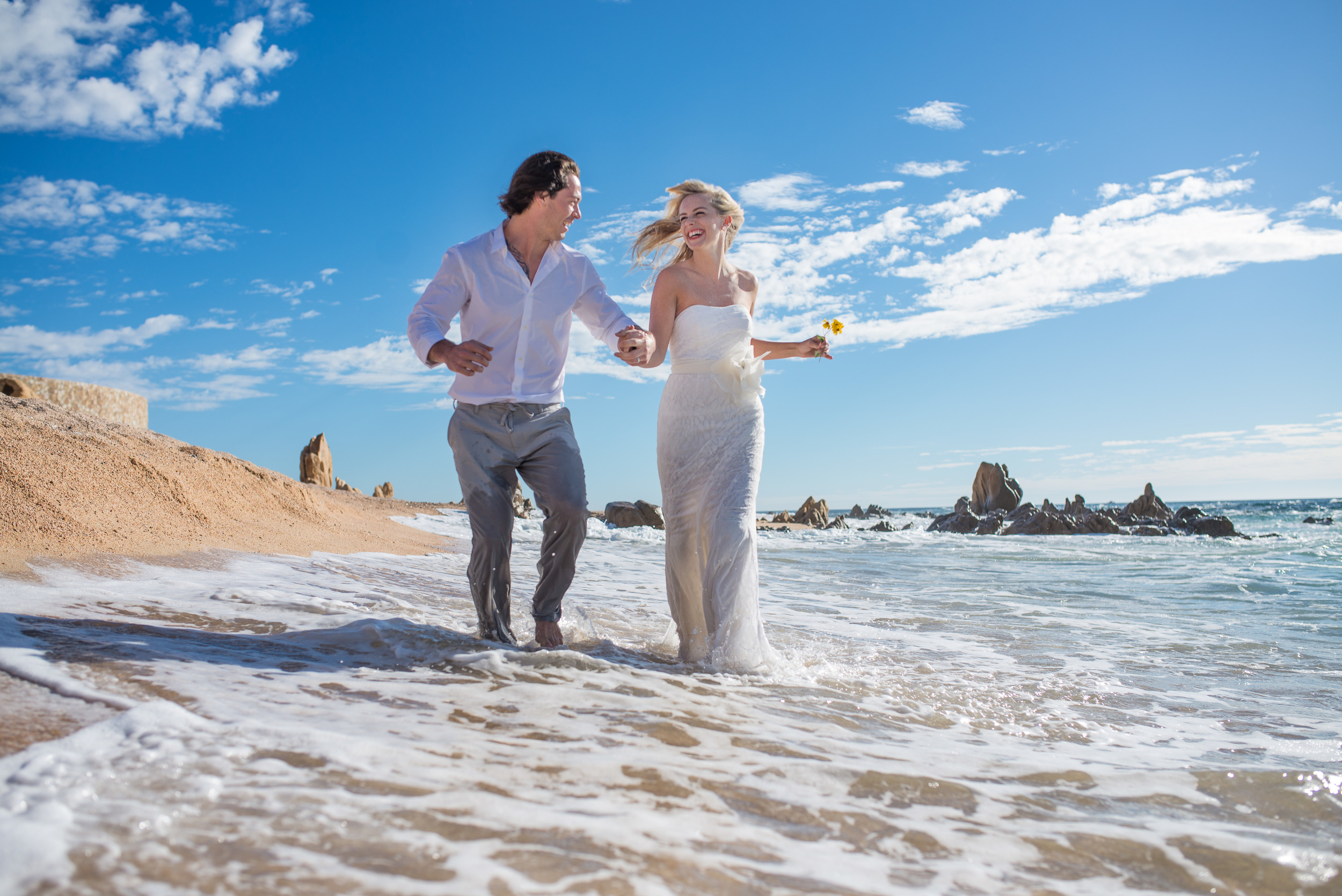 Bride and groom running and having fun on the sunny beaches of Cabo San Lucas