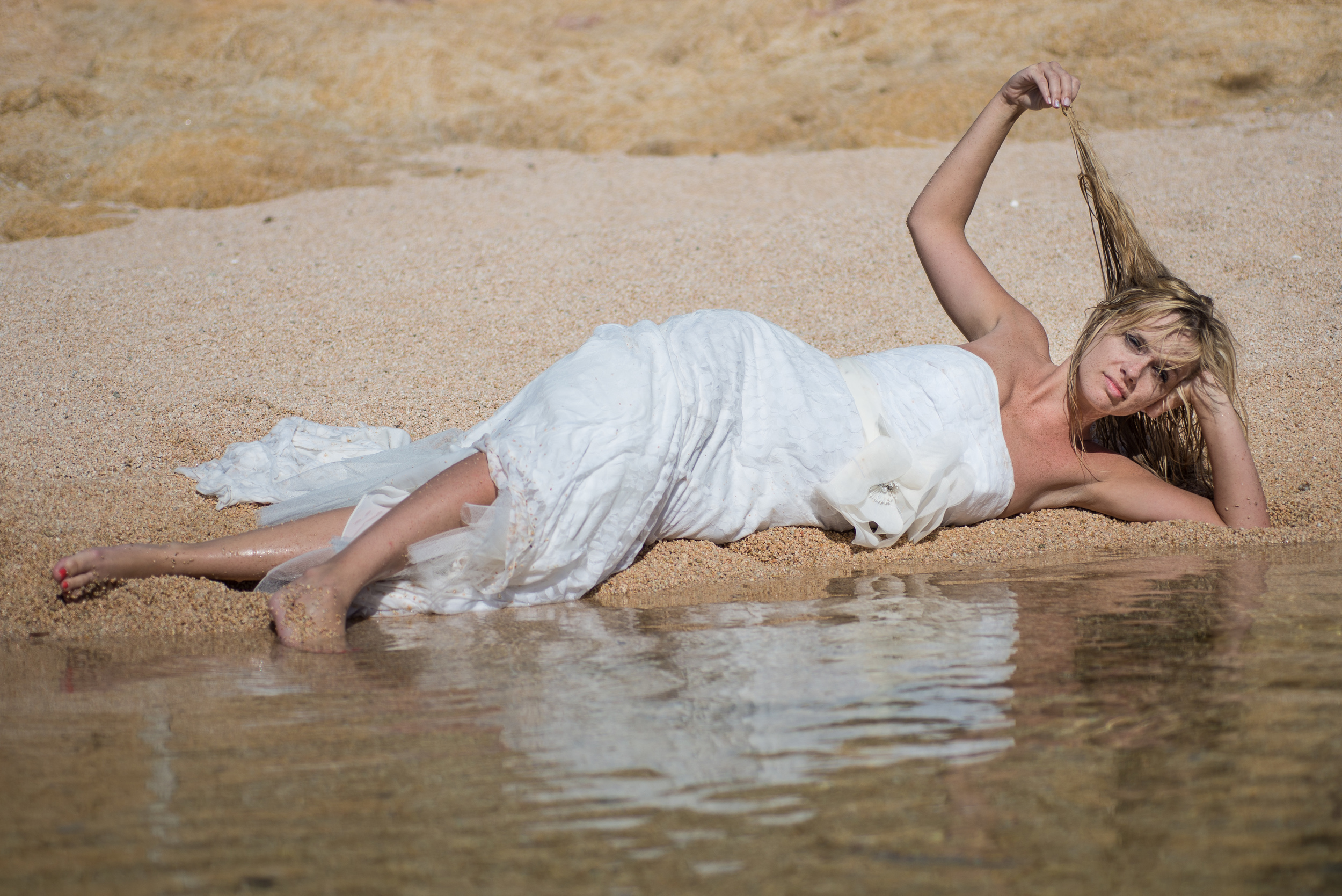 Bride is posing on a sandy beach in Cabo San Lucas during her trash the dress session