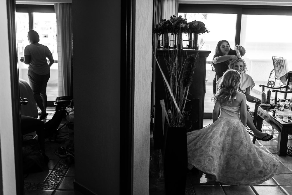 Bride getting ready for her destination wedding. Bride is sitting on the chair meanwhile a flower girl is playing around