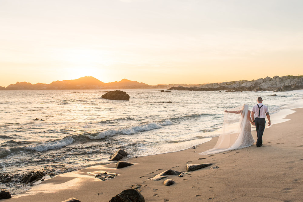 Bride and groom walking on the beach during the sunset