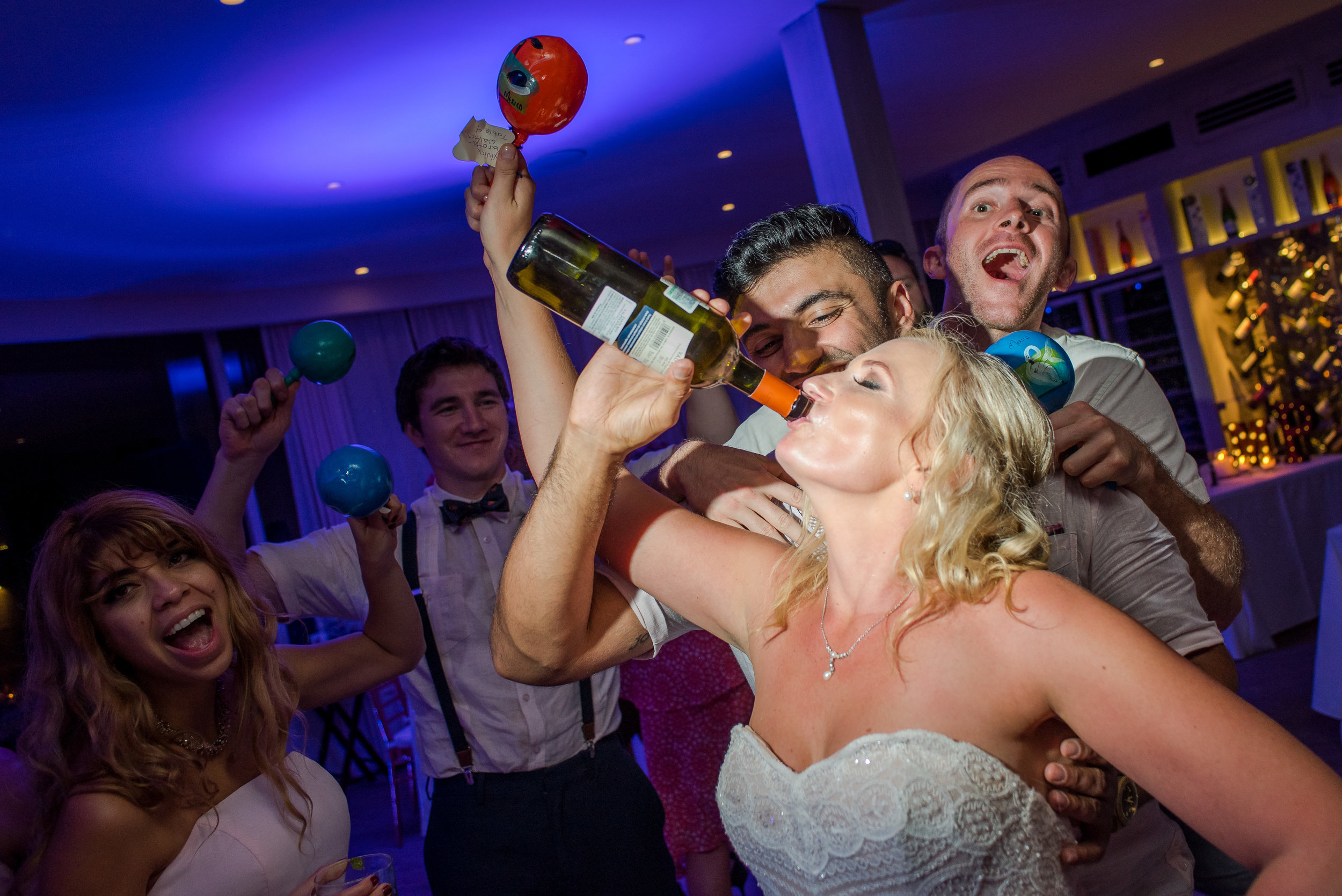 Bride drinking from the bootle and having a great time at her wedding party on the dance floor at sunset Monalisa