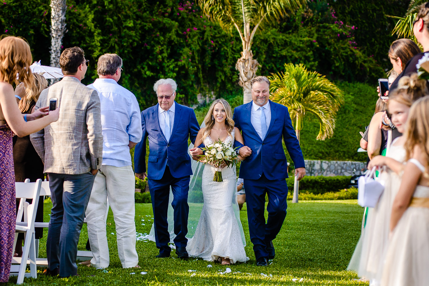  The bride is looking fabulous in her white gown and is smiling while walking in the beautiful garden Pueblo Bonito Sunset. GVphotographer is an amazing destination wedding photographer based in Cabo San Lucas, Mexico 