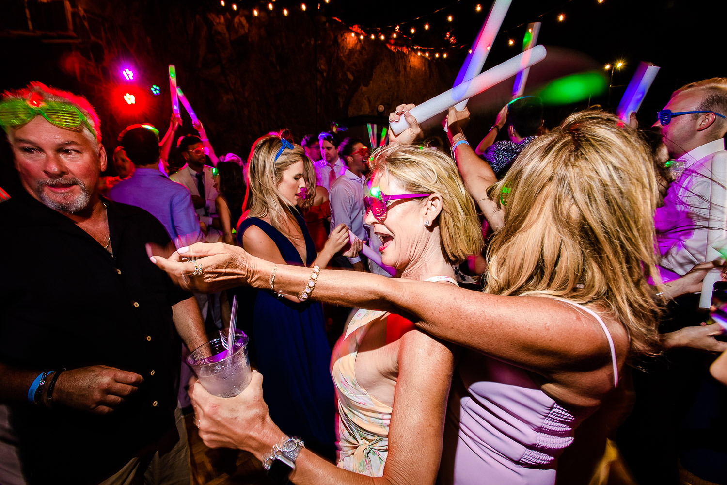  All the guests are dancing on the beats of music during the evening party of the couple . The picture captures the light effect of beautiful yellow light at the night time during the dance of the couple- destination wedding of the wonderful couple C