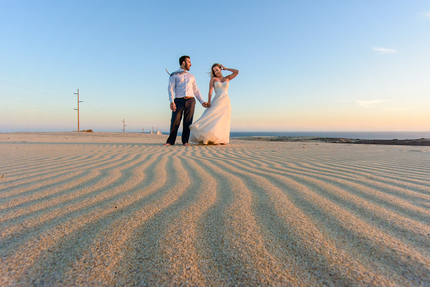  Bride and groom posing for talented wedding photographer GVphotographer on the dundes of Cabo San Lucas during the sunset 