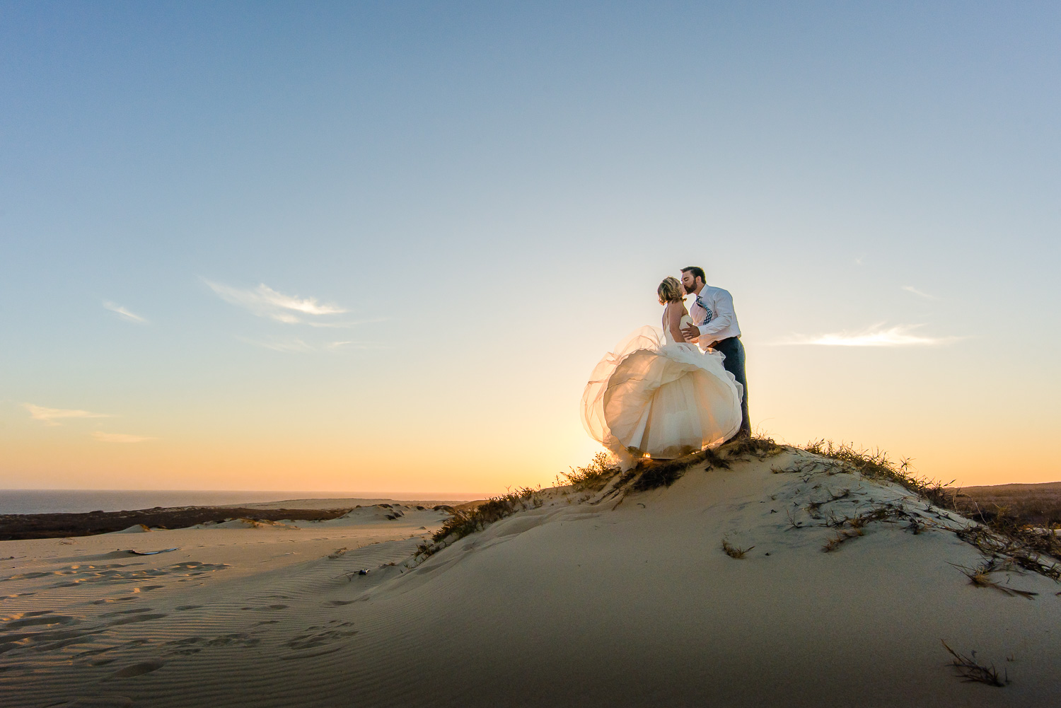  Bride and Groom kissing on top of a small dune during an amazing sunset in Cabo San Lucas 