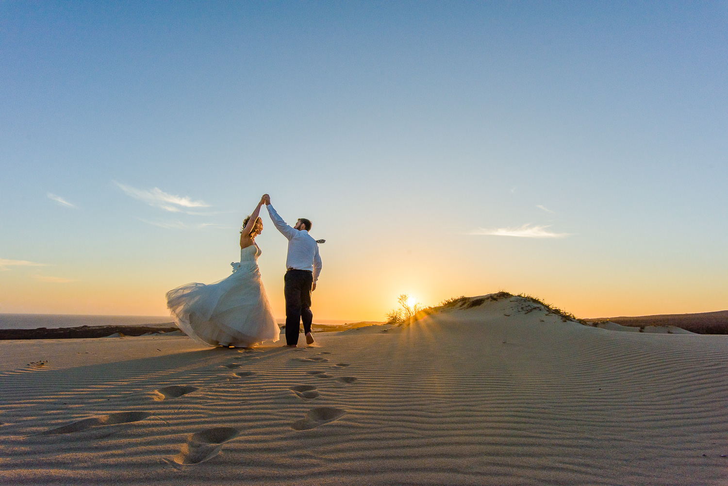  dancing on the dunes bride and groom with a beautifull sky and the dunes during a sunset photo session 